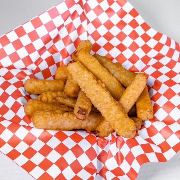 Golden-brown mozzarella sticks piled in a red and white checkered paper basket.