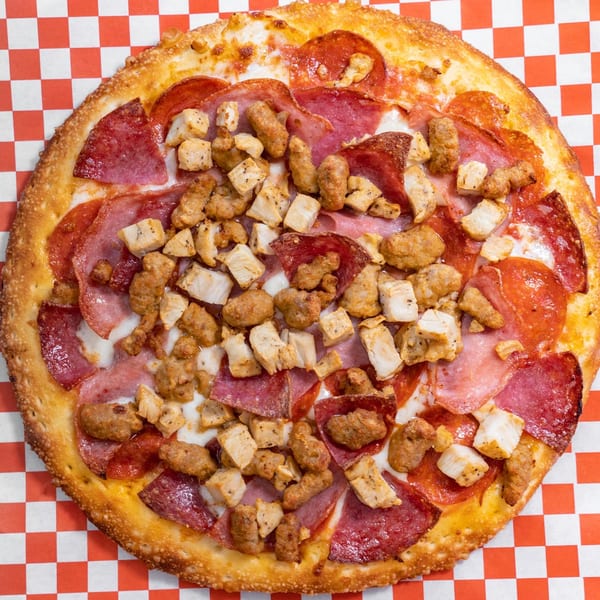 H and H Bar Grill's pizza with pepperoni, ham, chicken, and sausage on a checkered red and white background.