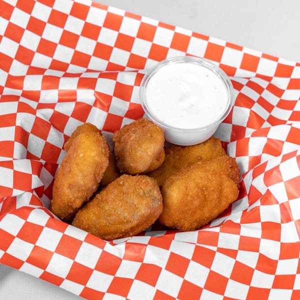 Golden-brown fried appetizers and a small cup of white dipping sauce in a red and white checkered basket.
