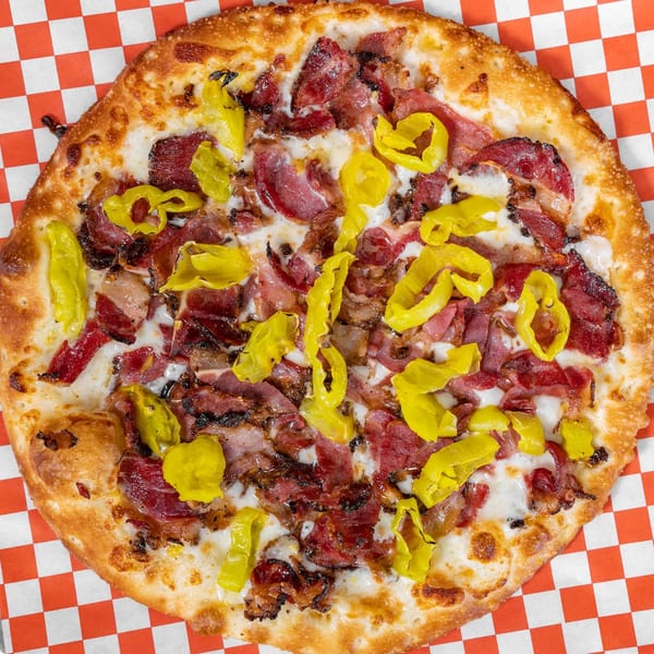 H and H Bar Grill pizza with pastrami, bacon, and banana peppers on a checkered paper.